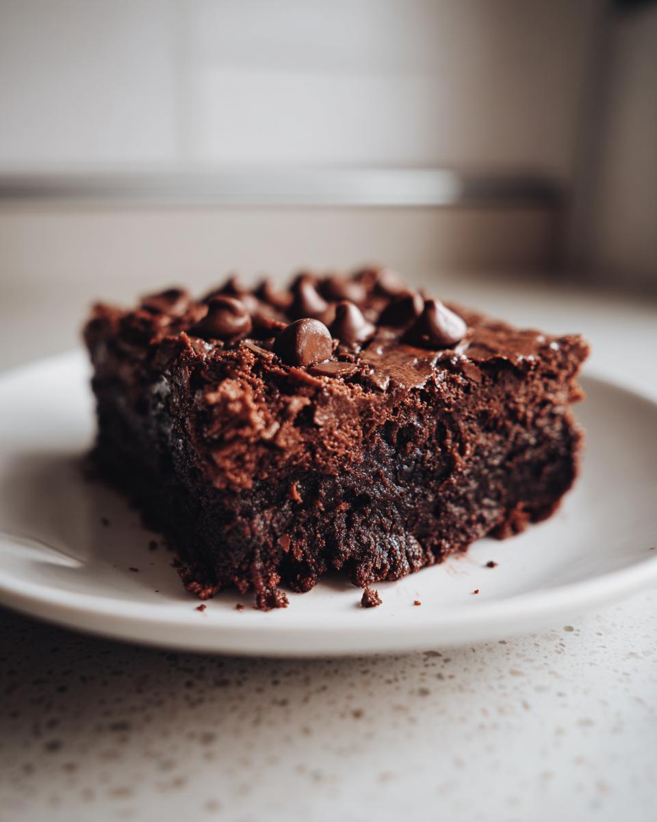 A close-up of a fudgy Cottage Cheese Microwave Brownie topped with melted chocolate chips on a white plate.