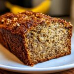Close-up of a freshly baked loaf of sugar free banana bread with a dark, caramelized crust and visible nuts.