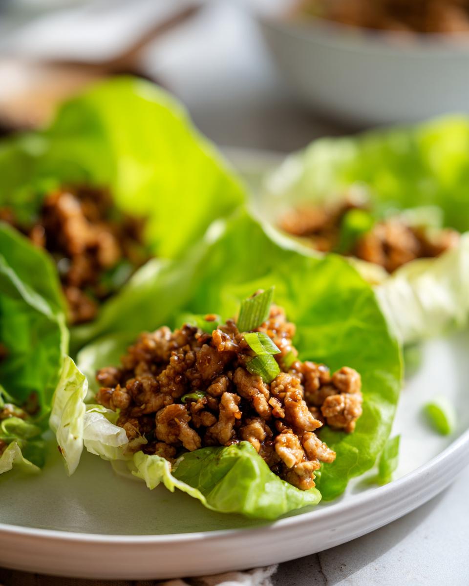 Close-up of delicious chicken lettuce wraps filled with savory ground chicken mixture and topped with green onions.