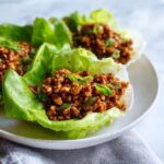 Close-up of savory chicken lettuce wraps filled with ground chicken mixture and topped with green onions.