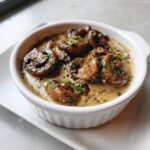 Close-up of whole sautéed mushrooms swimming in a rich, creamy mushroom sauce, garnished with fresh parsley.