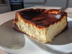 A close-up slice of creamy Basque cheesecake featuring a deeply caramelized, dark brown top.