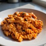 Close-up of a serving of cheesy enchilada pasta made with rotini, coated in a creamy orange sauce.