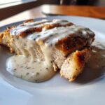 Close-up of sliced, seasoned chicken breast generously covered in a creamy, herbed garlic sauce.
