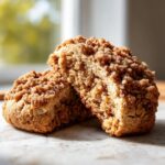 Two halves of a soft coffee cake cookie showing the thick, crumbly cinnamon topping and moist interior.