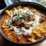 A close-up of a hearty bowl of crockpot lasagna soup topped with ricotta, meat sauce, Parmesan, and parsley.