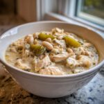Close-up of a hearty bowl of crockpot white chicken chili, featuring shredded chicken, white beans, and green chilies in a creamy sauce.