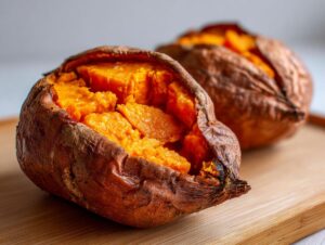 Close-up of a perfectly baked sweet potato, split open to show the fluffy, bright orange interior.