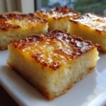 A close-up of a square slice of moist cassava cake featuring a rich, caramelized, and glossy golden-brown topping.