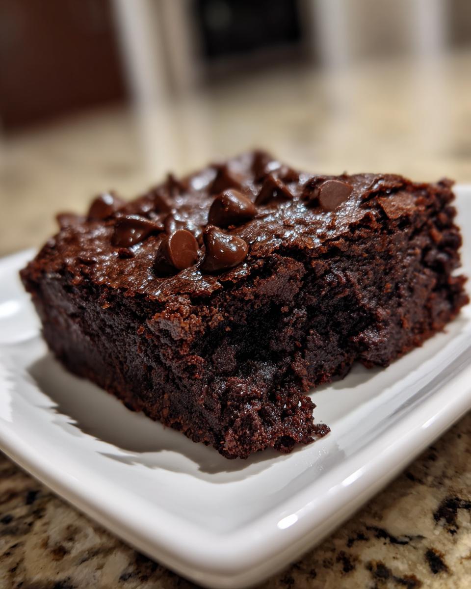 Close-up of a fudgy sweet potato brownies square topped with melted chocolate chips on a white plate.