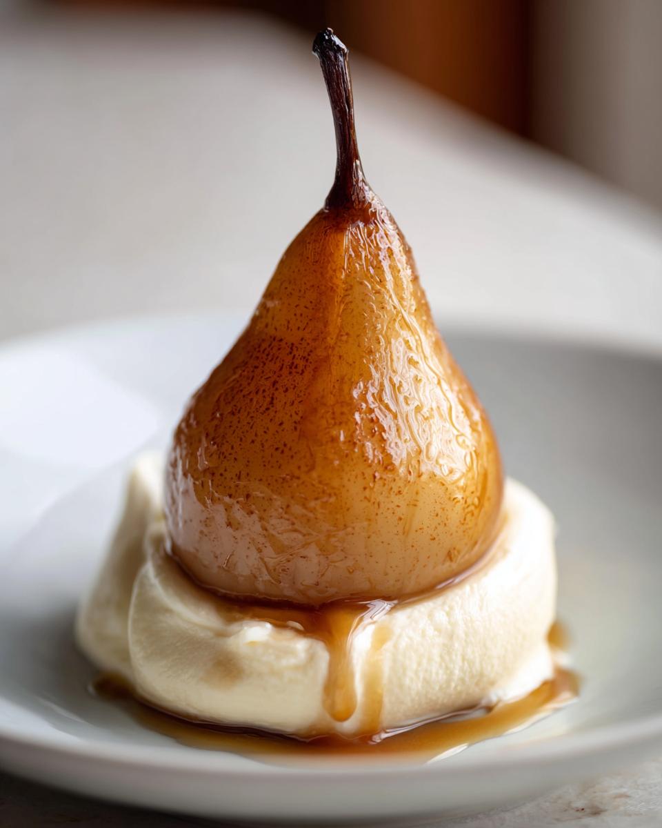 A close-up of a glistening, caramelized poached pear resting on a dollop of white cream, with syrup drizzling down.