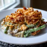 A close-up serving of creamy green bean casserole topped generously with crispy fried onions.