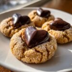 Four delicious kiss cookies, rolled in sugar, each topped with a shiny, melted chocolate heart.