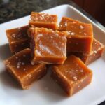 A pile of rich, chewy squares of homemade caramel sprinkled with sea salt flakes.
