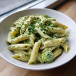 Close-up of creamy broccoli pasta made with penne, topped with fresh parsley.