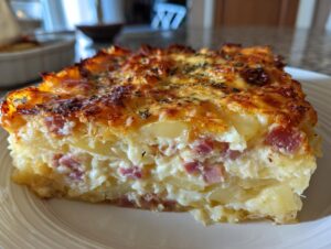A thick, layered slice of scalloped potatoes and ham with a creamy sauce and a golden, bubbly cheese crust.