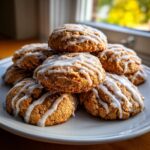 A stack of soft, freshly baked persimmon cookies drizzled with white glaze, sitting on a white plate.