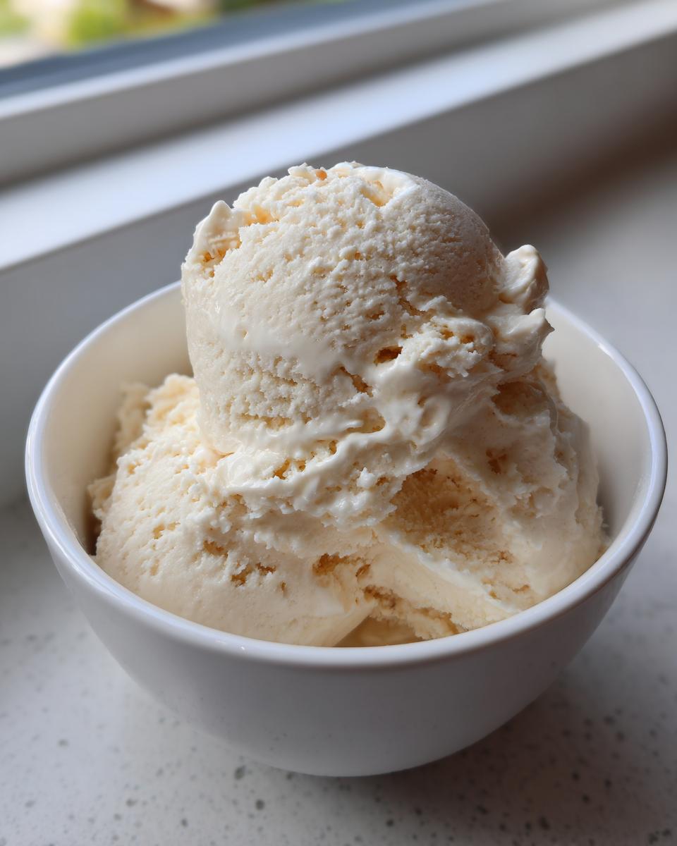 Close-up of two scoops of creamy vanilla protein ice cream served in a small white bowl.