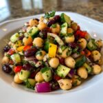 Close-up of a colorful, fresh bean salad featuring chickpeas, kidney beans, cucumber, and red onion.