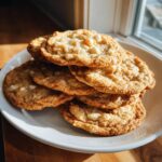 A tempting stack of freshly baked white chocolate macadamia nut cookies piled high on a white plate.