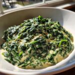 A close-up of rich, homemade creamed spinach served in a white bowl, highlighting the creamy sauce.