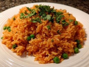 A plate of fluffy, orange-colored mexican rice recipe mixed with bright green peas and topped with fresh cilantro.