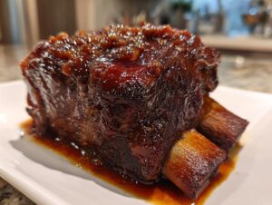Close-up of a thick, tender braised short ribs piece covered in a rich, dark glaze, resting in sauce.
