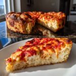 A thick slice of pizza featuring a fluffy cottage cheese pizza crust topped with melted cheese and tomato sauce.