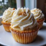 Three delicious banana pudding cupcakes topped with thick vanilla frosting and a sprinkle of crushed wafer.