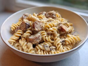 A close-up of creamy kielbasa pasta made with rotini noodles, rich sauce, and sliced sausage.
